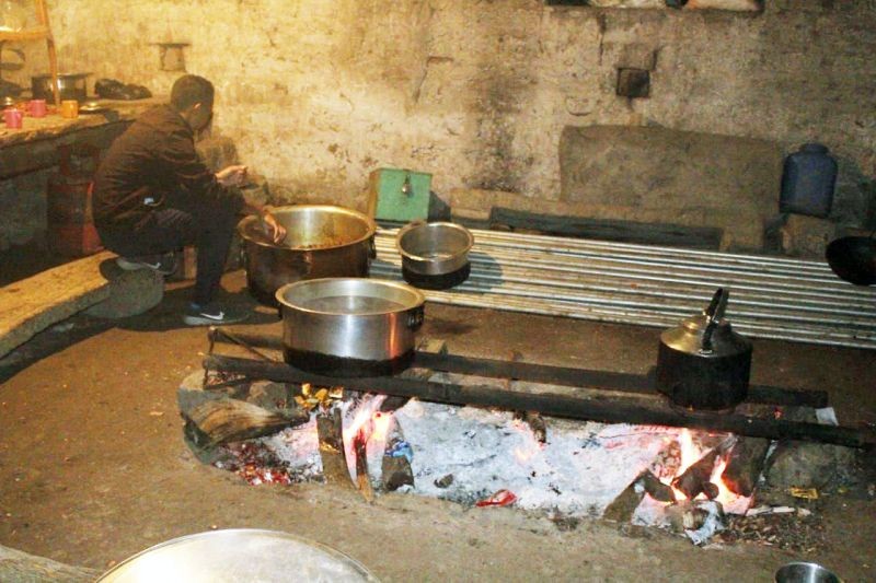 A man sits near a fireplace where food is cooked for the whole members of the khel. (Morung Photo)